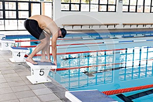 Caucasian young male swimmer preparing to dive into an indoor pool