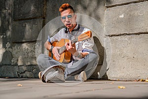 Caucasian young man playing the guitar outdoors. Music, art, creativity concept