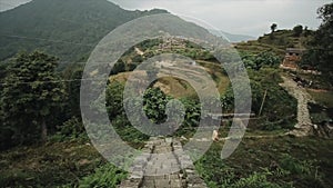 A caucasian young man running down nepalese stairs, trek. Landscape, terraced rice fields, hills, mountains, forest