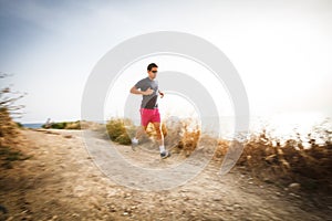 Caucasian young man running on a seacost path