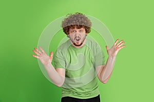 Caucasian young man`s monochrome portrait on green studio background