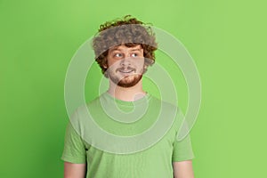 Caucasian young man`s monochrome portrait on green studio background