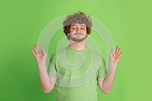 Caucasian young man`s monochrome portrait on green studio background