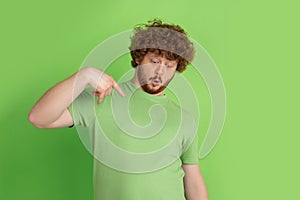 Caucasian young man`s monochrome portrait on green studio background