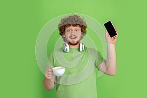 Caucasian young man`s monochrome portrait on green studio background