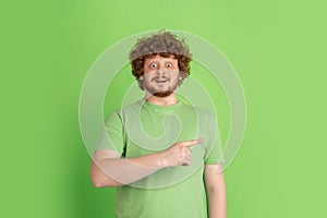 Caucasian young man`s monochrome portrait on green studio background