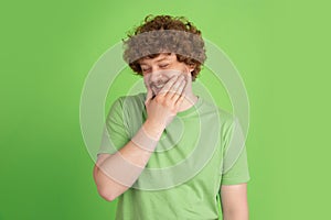 Caucasian young man`s monochrome portrait on green studio background
