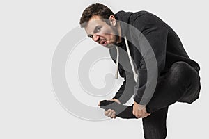 Caucasian young man takes off his dirty socks while looking into the camera . Isolated on white background