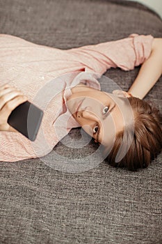Caucasian young man using mobile phone while lying indoor. Corresponded, chatting or browsing. Concept browsing, rest photo