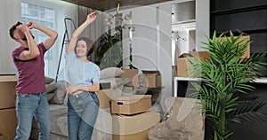 Caucasian young married family couple having fun and dancing in living room in new home together. New life begins