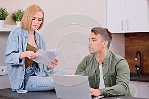 Caucasian young spouses sitting with laptop and documents at home