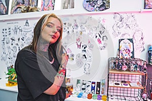 Caucasian young tattooed girl in a black T-shirt in the tattoo salon, medium shot