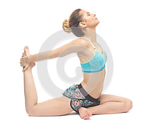 Caucasian young well fit girl making yoga Pigeon pose with one-hand right leg grab