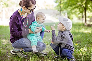 Caucasian young woman with baby daughter and preschool son enjoying beautiful day in park