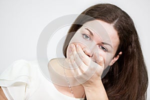 Caucasian young woman covering her mouth with hand, grey background