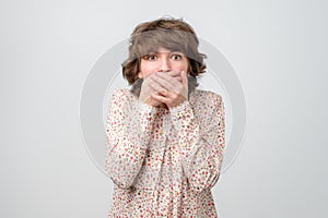 Caucasian young woman covering her mouth trying not to make any noise.