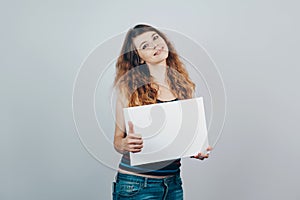 Caucasian young woman with curly hair showing thumbs up gesture and holding a  blank empty white canvas in her hand.