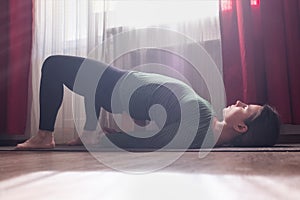 Caucasian young woman doing yoga exercise ardha chakrasana