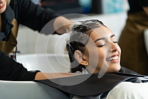 Caucasian young woman get hair washed by Hairdresser stylist in salon. Beautiful customer girl lying down on salon washing bed