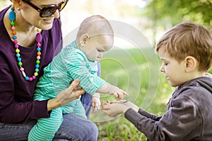 Caucasian young woman holding baby daughter while preschool showing bugs on his hand