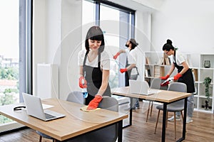 Caucasian young woman holding sponge and detergent cleaning on table in office.