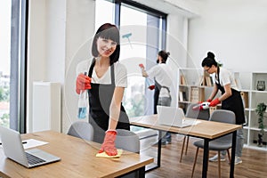 Caucasian young woman holding sponge and detergent cleaning on table in office.