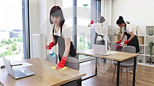 Caucasian young woman holding sponge and detergent cleaning on table in office.