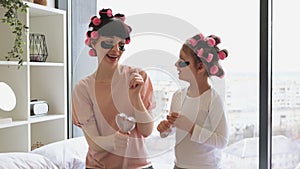 Caucasian young woman and little girl curling hair and applying eye patches.