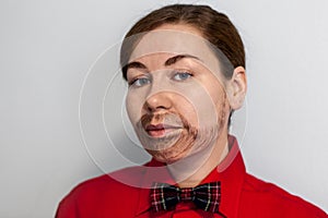 Caucasian young woman with painted beard. Wearing lake a man in red shirt and a bow tie. Male hairstyle