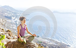 Caucasian young woman practicing yoga while sitting in lotus pose outdoors