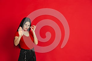 Caucasian young woman`s monochrome portrait on red studio background, emotional and expressive