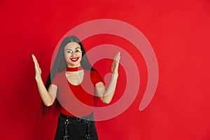 Caucasian young woman`s monochrome portrait on red studio background, emotional and expressive