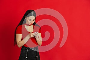 Caucasian young woman`s monochrome portrait on red studio background, emotional and expressive