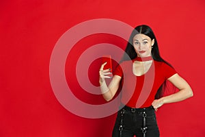 Caucasian young woman`s monochrome portrait on red studio background, emotional and expressive