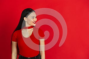 Caucasian young woman`s monochrome portrait on red studio background, emotional and expressive