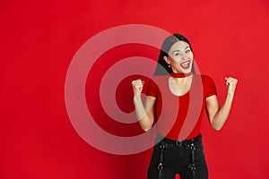 Caucasian young woman`s monochrome portrait on red studio background, emotional and expressive