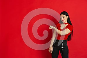 Caucasian young woman`s monochrome portrait on red studio background, emotional and expressive