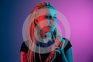 Caucasian young woman`s portrait on gradient background in neon light