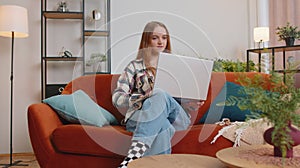 Caucasian young woman sitting on sofa opening laptop pc starting work online in living room at home