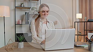 Caucasian young woman sitting at table opening laptop pc starting work online in room at home office