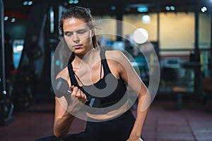 Caucasian young woman in sportswear lifting dumbbell  in fitness gym