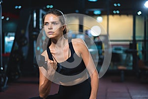 Caucasian young woman in sportswear lifting dumbbell  in fitness gym