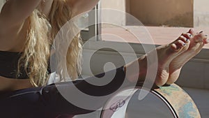 Caucasian young woman in a sportswear practicing yoga poses with pilates exercise wheel for back exercises at home