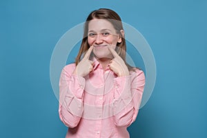 Caucasian young woman tries to pretend she is happy in front of people