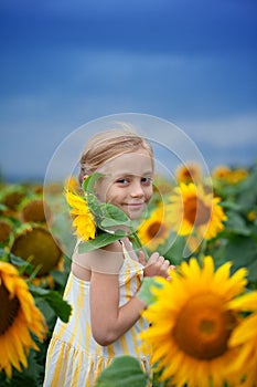 Caucasiann smiling cute girl with big yellow sunflower on shoulder of child