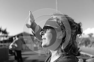 caucasican adult woman in an amusement park, looking at the sun and covering his hand causing shadows on his face