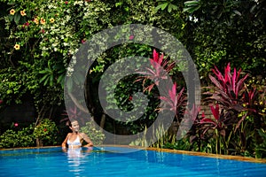 Caucasican woman rests in blue pool in tropics