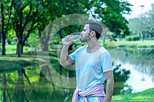 Caucasion man thirsty and drinking water from pet bottle in public park