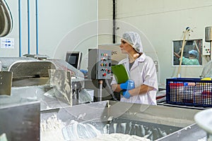 caucasion woman working in a food factory wearing protective clothes and gloves