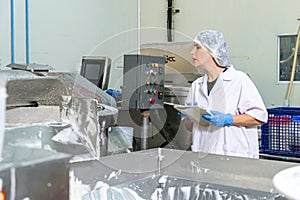 caucasion woman working in a food factory wearing protective clothes and gloves